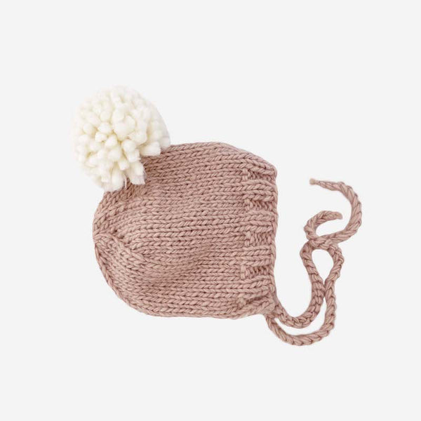 Hand knit winter baby bonnett. Features blush body and ties, with cream colored pom pom.