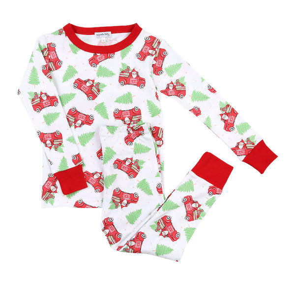 Magnolia Baby Christmas pajamas in adorable Santa, tree, and red truck print. Features red cuffs on top and pants. Perfect for Christmas morning!