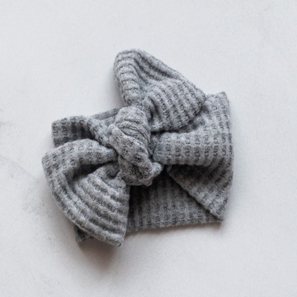 Baby top knot bow headband made of grey waffle material. 