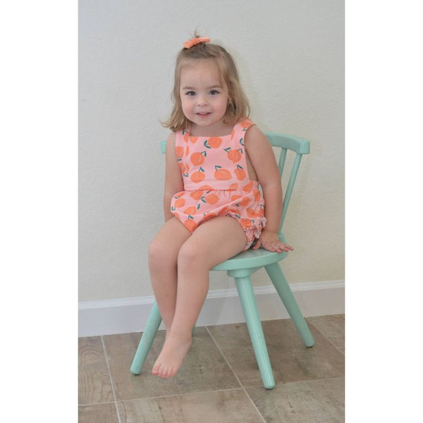 Baby and toddler girl's peach romper with adorable cross back straps and ruffle detail on the back. 